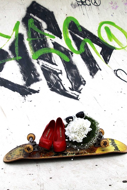Skateboard mit Hochzeitsstrauss und roten Pumps